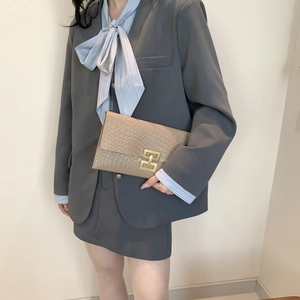 Elegant khaki snakeskin patterned clutch with gold buckle paired with a grey suit