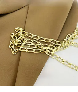Detailed close-up of a glossy gold metal replacement chain strap on brown fabric