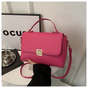 Close-up of rose pink leather handbag with crocodile pattern and gold metal lock detail