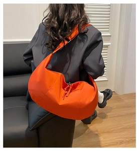 Model wearing a bright orange large capacity crossbody bag with wide shoulder strap