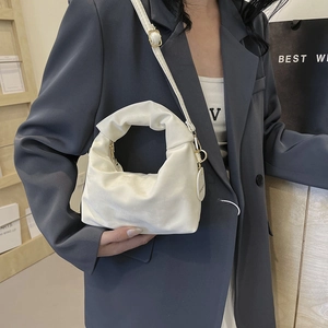 Chic beige ruched shoulder bag with gold hardware shown on a stylish fashion model