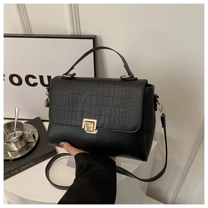 Detailed close-up of crocodile textured black PU leather bag with golden metal rotary lock