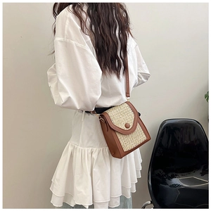 Detail of woven straw and brown leather crossbody bag worn by a model in profile view