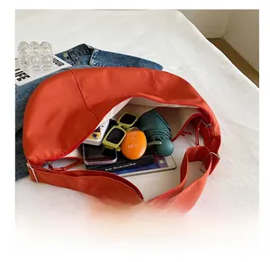 Interior view showing large capacity of the orange nylon crescent bag with daily essentials