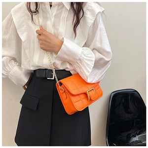 Detail shot of bright orange quilted faux leather shoulder bag with gold chain strap
