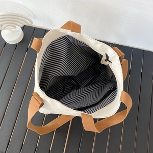 Détail du sac cabas en toile montrant la doublure rayée et la poche zippée interne