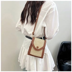 Detail of woven straw and brown leather crossbody bag with adjustable strap on a model