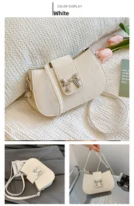 Detailansicht der cremeweißen Handtasche mit Faltenstruktur und silberner Schleife