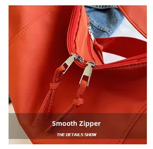 Close-up of smooth double zipper and durable strap on the orange nylon crossbody bag