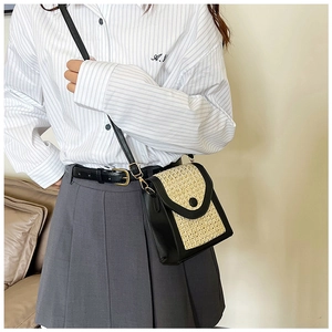 Detail of a mini crossbody bag featuring black trim and beige woven straw texture with a buckle