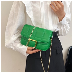 Detail of emerald green quilted crossbody bag with golden rectangular buckle and chain strap