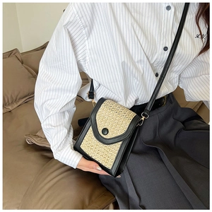 Detail showing woven straw and black leather crossbody bag with a round snap button