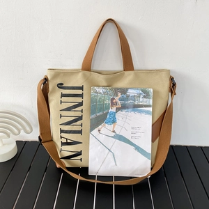 Détail du sac cabas en toile beige avec imprimé noir et finitions en cuir marron