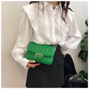 Detail of green quilted PU leather crossbody bag with gold buckle and metal chain strap