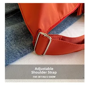 Detail showing the adjustable shoulder strap and silver buckle of the orange crossbody bag
