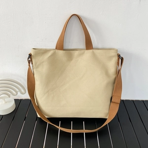 Détail du sac cabas en toile montrant la texture beige et les anses tissées marron