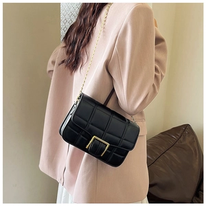 Side view of a black quilted chain bag styled with a pink blazer for a trendy look