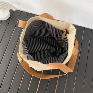 Vue de dessus d'un grand sac cabas en toile avec doublure à rayures bleues et fermeture