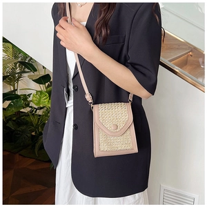 Detail of mini straw crossbody bag with pink leather trim and beige woven texture