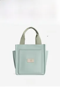 Detailed front view of mint green canvas tote bag featuring a square pocket and N patch