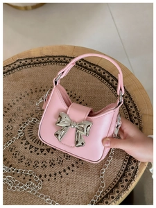 Detailed view of pink PU leather mini handbag with a large silver metal bow buckle