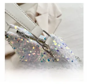Détail du crochet en métal argenté et paillettes colorées sur un sac à main blanc