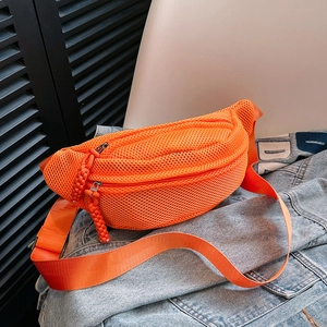 Detail of orange mesh crossbody bag with dual zippers and woven pullers on denim