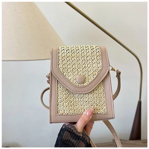 Detail showing woven straw texture and beige faux leather stitching on small crossbody bag