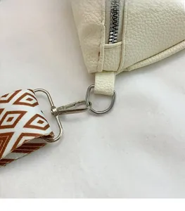 Detail of silver hardware lobster clasp and vintage geometric strap on off-white bag