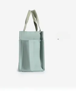 Detail of light green canvas tote bag with functional front pocket and thick woven texture