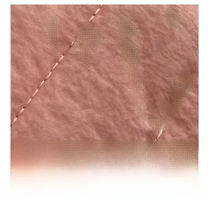 Primer plano de tela acolchada rosa con costuras diagonales para bolso de hombro suave