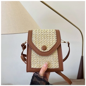 Detail of a mini straw crossbody bag with brown faux leather trim and round buckle