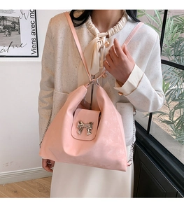 Detail view of pink bow crossbody bag with silver chain and premium matte texture