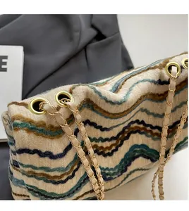 Detail of tweed wavy pattern bag with golden chain strap and metallic eyelets
