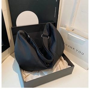 Detail of black crossbody dumpling bag with silver hardware in premium gift box packaging