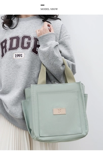 Detail view of light green canvas tote bag with side pockets and leather N-label