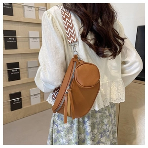 Close-up of brown textured leather crossbody bag with patterned wide strap and small round pouch