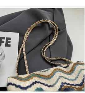 Detail view of woven shoulder bag with wave patterns and metal chain handle textures