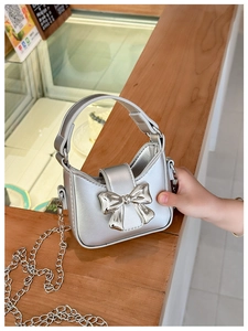 Detailed view of silver mini handbag with large metallic bow and chain strap