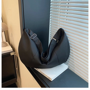 Close-up of black crescent shoulder bag with silver adjustable buckle on nylon fabric