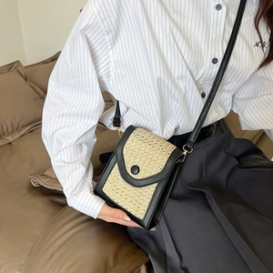 Quilted straw mini crossbody bag with black trim and gold hardware on female model