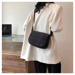 Detalle de bolso bandolera acolchado negro de nailon con correa ajustable en una modelo