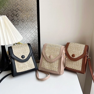 Three woven straw crossbody bags with leather patchwork and round buckles in a home setting