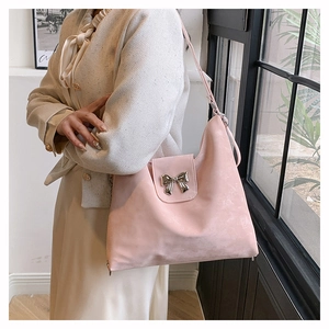 Detailed view of pink shoulder bag featuring a metallic butterfly bow clasp and matte texture