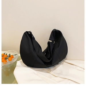 Macro shot of minimalist black nylon crescent bag with wide strap on white cloth