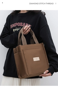 Detail view of a brown canvas tote bag featuring an exterior pocket and N-logo leather patch