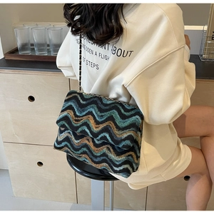 Detail of plaid tote bag with wavy knit pattern and metallic chain strap shown on model