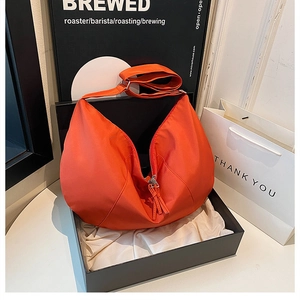 Detail of a bright orange nylon crescent hobo bag with adjustable strap in a gift box