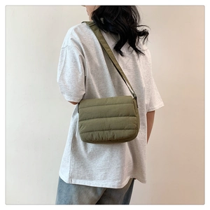Bolso bandolera verde militar acolchado con textura suave y correa ajustable usado por modelo
