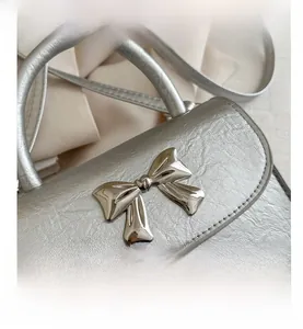 Close-up of silver textured leather handbag with a metallic bow buckle detail
